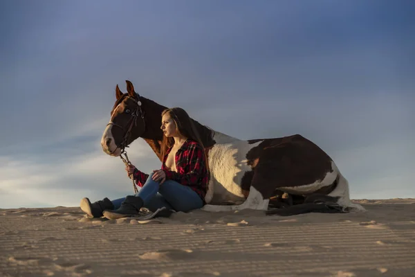 Una encantadora modelo morena pasea su caballo por el desierto en un día de verano — Foto de Stock