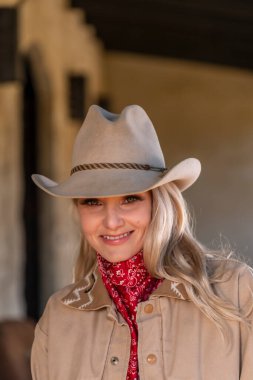 Kovboy gibi giyinmiş muhteşem sarışın bir manken. Açık havanın tadını çıkarıyor.