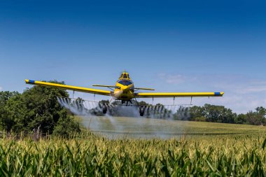 A crop duster applies chemicals to a field of vegetation. clipart
