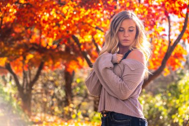 Muhteşem sarışın bir model parkta sonbahar gününün tadını çıkarıyor.