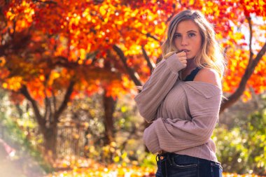 Muhteşem sarışın bir model parkta sonbahar gününün tadını çıkarıyor.