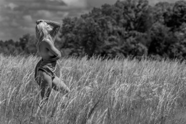 Açık havada çıplak poz veren muhteşem bir sarışın manken.