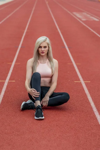 A beautiful young college athlete prepares herself for a track meet at a local university