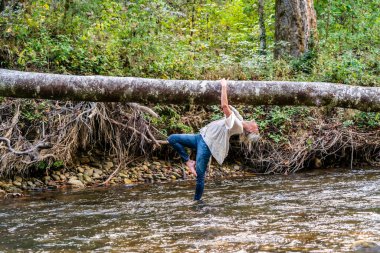 Muhteşem bir sarışın manken bir yaz günü ormanda bir nehirde oyun oynuyor.