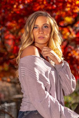 Muhteşem sarışın bir model parkta sonbahar gününün tadını çıkarıyor.