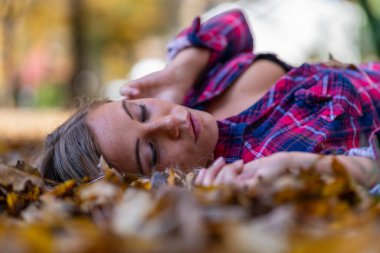 Muhteşem sarışın bir model parkta sonbahar gününün tadını çıkarıyor.