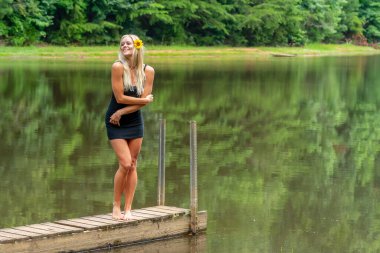 Muhteşem sarışın bir manken, yaz gününün tadını çıkarırken göletin kenarında poz veriyor.