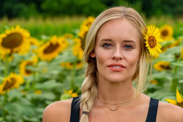 Sarışın bir model, yaz gününün tadını çıkarırken ayçiçeği tarlasında poz veriyor.