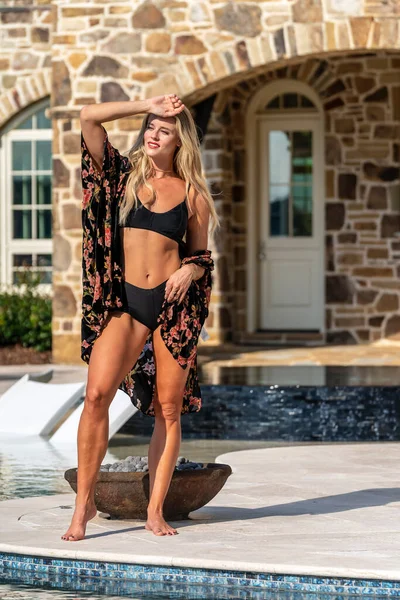 A gorgeous blonde bikini model enjoys a summers day by the pool