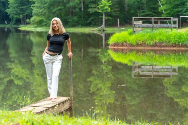 Sarışın bir model, yaz gününün tadını çıkarırken ayçiçeği tarlasında poz veriyor.