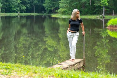 Sarışın bir model, yaz gününün tadını çıkarırken ayçiçeği tarlasında poz veriyor.