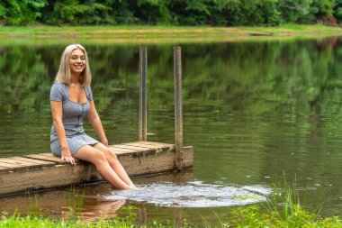 Sarışın bir model, yaz gününün tadını çıkarırken ayçiçeği tarlasında poz veriyor.