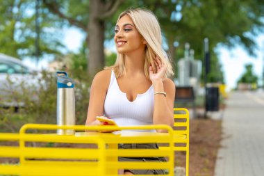 Sarışın bir model yaz gününün tadını çıkarırken dışarıda poz veriyor.