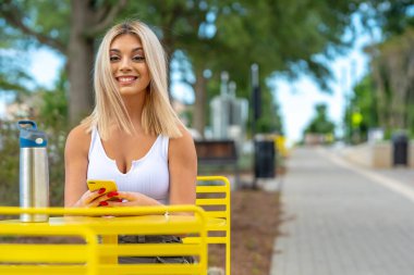 Sarışın bir model yaz gününün tadını çıkarırken dışarıda poz veriyor.