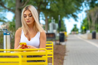 Sarışın bir model yaz gününün tadını çıkarırken dışarıda poz veriyor.