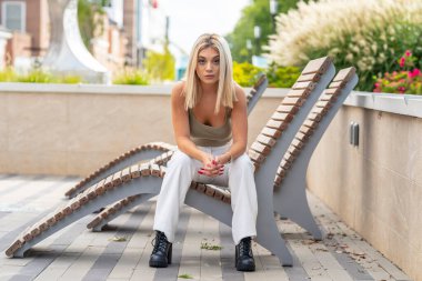 Sarışın bir model yaz gününün tadını çıkarırken dışarıda poz veriyor.