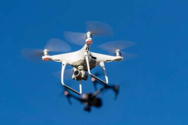 Bir grup dron havada mavi gökyüzüne karşı uçuyor.