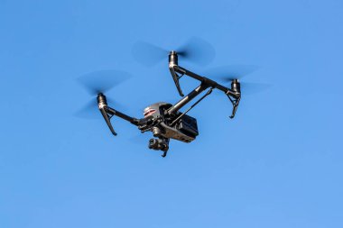 Bir grup dron havada mavi gökyüzüne karşı uçuyor.
