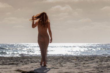 Gün batımında kumsalda uzanan muhteşem bir esmer bikini mankeni.