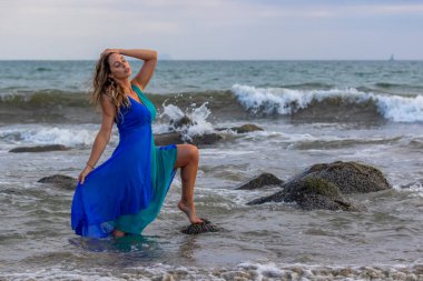 Güzel bir esmer İspanyol manken gün batımında sahilde poz veriyor.