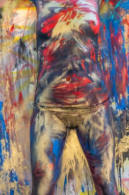 Çıplak bir kadın ev ortamında renkli boya ile boyanır.