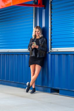 Sonbahar kıyafetleriyle dışarıda poz veren güzel bir sarışın manken.