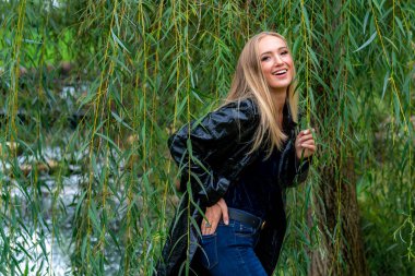 Sonbahar kıyafetleriyle dışarıda poz veren güzel bir sarışın manken.