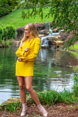 Sonbahar kıyafetleriyle dışarıda poz veren güzel bir sarışın manken.