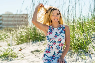 Sarışın bir kadın kumsalda tek başına eğleniyor.