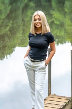 Sarışın bir model, yaz gününün tadını çıkarırken ayçiçeği tarlasında poz veriyor.