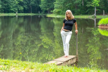 Sarışın bir model, yaz gününün tadını çıkarırken ayçiçeği tarlasında poz veriyor.