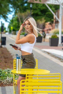 Sarışın bir model yaz gününün tadını çıkarırken dışarıda poz veriyor.