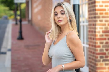 Sarışın bir model yaz gününün tadını çıkarırken dışarıda poz veriyor.