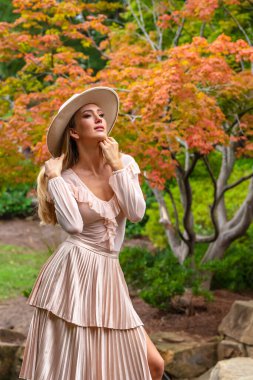 Sonbahar kıyafetleriyle dışarıda poz veren güzel bir sarışın manken.