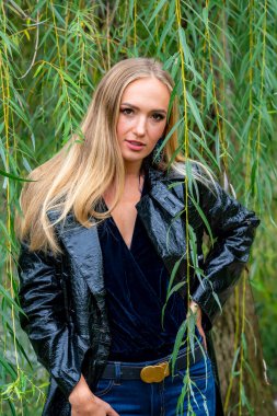 Sonbahar kıyafetleriyle dışarıda poz veren güzel bir sarışın manken.