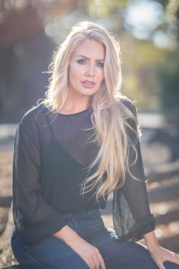 Sonbahar kıyafetleriyle dışarıda poz veren güzel bir sarışın manken.