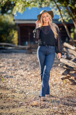 Sonbahar kıyafetleriyle dışarıda poz veren güzel bir sarışın manken.