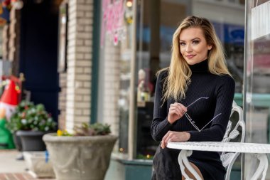 Muhteşem sarışın bir kadın, rahat bir elbise ve cekete sarılmış küçük bir kasabada geziniyor. Altın yapraklarla çevrili, sıcacık gülümsüyor, temiz havanın ve büyüleyici manzaranın tadını çıkarıyor..