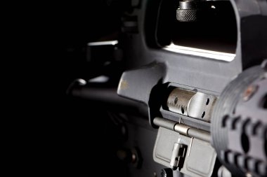 AR-15 tüfeği keskin detaylarla çekilir. Stüdyoda derin siyah bir arkaplanda, parlak çizgileri ve çarpıcı ışıklandırmayla vurgulanmış metalik bitişiyle çekilir..