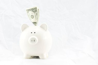 Beyaz bir domuz kumbarası için bir manşet stüdyoda ele geçirildi. Tasarruf ve finansal büyümeyi ön plana çıkaran banknotlar, temiz ve iyi ışıklandırılmış bir arka plana yerleştirildi..