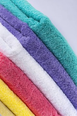 Renkli havlular stüdyoda temiz bir arka plana karşı çekiliyor, canlı renkler, yumuşak dokular ve düzgün bir düzenleme net, iyi aydınlatılmış detaylarla vurgulanıyor..