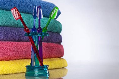 Renkli diş fırçaları stüdyoda temiz bir arkaplana karşı çekilen canlı havlular, parlak renkler, yumuşak dokular ve parlak, iyi aydınlatılmış detaylar ile düzenlenir..