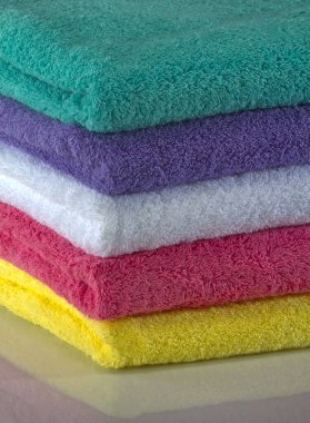 Renkli havlular stüdyoda temiz bir arka plana karşı çekiliyor, canlı renkler, yumuşak dokular ve düzgün bir düzenleme net, iyi aydınlatılmış detaylarla vurgulanıyor..