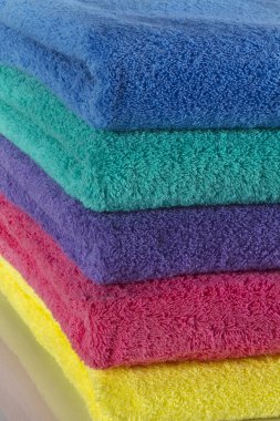 Renkli havlular stüdyoda temiz bir arka plana karşı çekiliyor, canlı renkler, yumuşak dokular ve düzgün bir düzenleme net, iyi aydınlatılmış detaylarla vurgulanıyor..