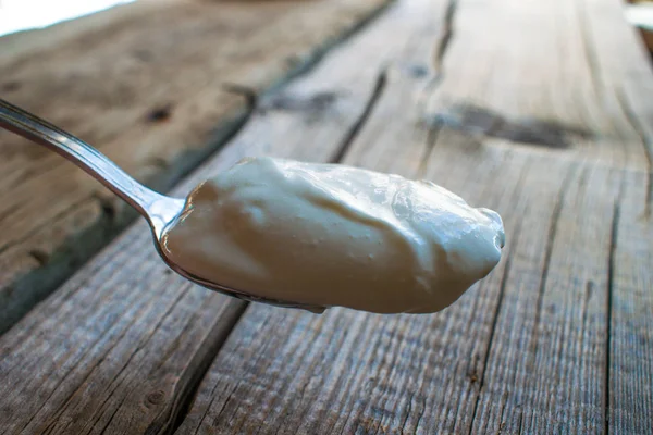 A spoonful of sour cream over the table. — Stock Photo, Image