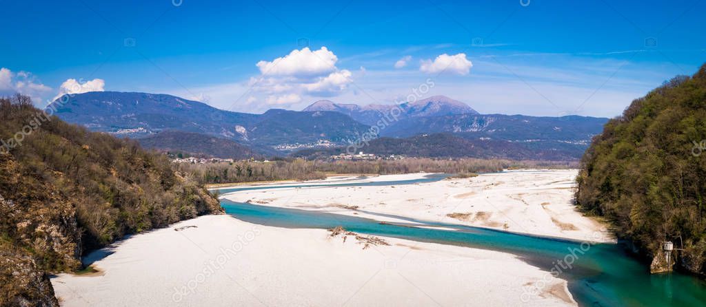 Turquoise braided river Tagliamente from bridge Pinzano with mountains Flagjel, Cuel di Forchia and Cuar on horizon in spring in Italy