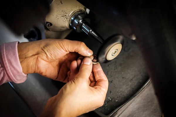 Jeweler polishes a gold ring on a bench grinder in an authentic jeweller\'s workshop