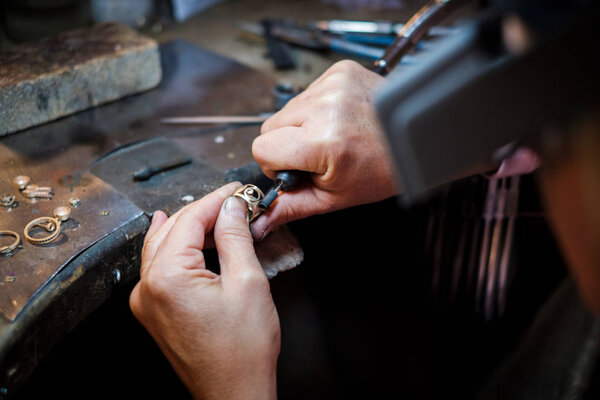 Jeweler polishes a gold ring on an old workbench in an authentic jewelry workshop