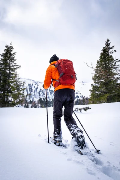 在一个多云的冬日里 在度假村霍恩图恩 穿着橙色夹克雪穿雪的男子覆盖着谢贝拉姆 — 图库照片