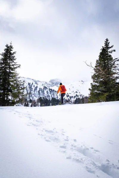 在一个多云的冬日里 在度假村霍恩图恩 穿着橙色夹克雪穿雪的男子覆盖着谢贝拉姆 — 图库照片